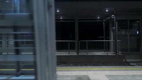 Fahrgastansicht-Aus-Dem-Inneren-Des-Zuges,-Der-Nachts-Am-Bahnhof-Vorbeifährt