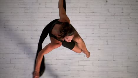 Close-up-of-an-sporty-woman-doing-aerial-yoga-or-air-dancing-while-hanging-and-spinning,-fitness-concept