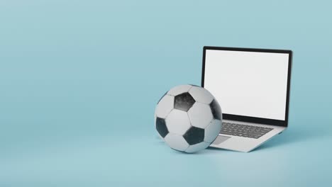 Soccer-ball-in-front-of-laptop-with-white-screen-descends-into-frame