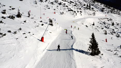 The-drone-follows-skiers-on-Chopok-mountain-in-Jasna,-Low-Tatras,-Slovakia