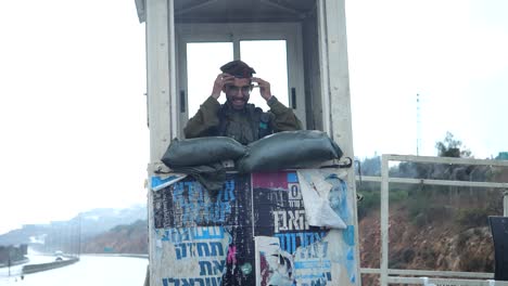 Happy-Israel-Soldier-from-IDF-Wearing-Beret-Standing-on-Sentry-Duty-Inside-Frontier-Road-Checkpoint-Booth-or-Sentry-Box-on-Rainy-Day---slow-motion