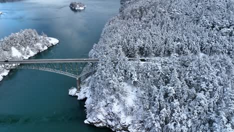 Ultra-wide-establishing-aerial-view-of-Deception-Pass-bridge-while-snow-covers-the-ground