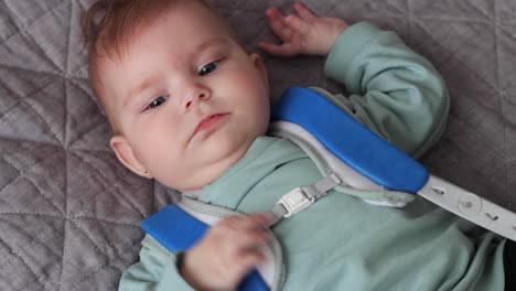 Baby-girl-in-Pavlik-Harness-to-correct-Hip-Dysplasia-lying-on-blanket