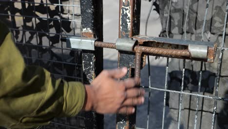 Hand-Eines-Bewaffneten-Soldaten-Der-Israelischen-Armee,-Der-Das-Tor-Mit-Einem-Metallriegel-Draußen-Schließt