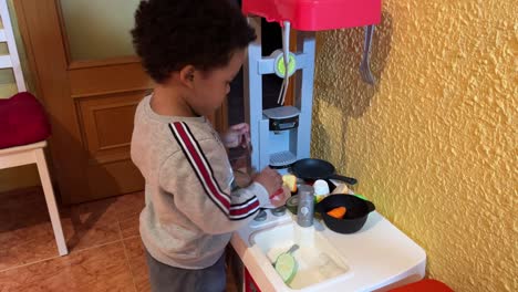 Lovely-two-year-old-black-baby,-mix-raced,-playing-at-home-to-cook-in-his-toy-kitchen