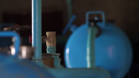 Close-Up-View-Of-Piping-Inside-Water-Pump-Room-With-Blurred-Background-Of-Blue-Tank