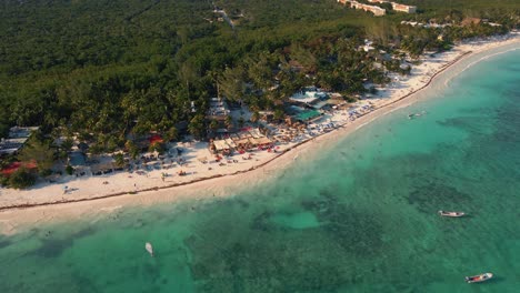 Flying-over-the-turquoise-waters-of-the-Caribbean-sea-to-reveal-the-beachfront-tourism-industry-and-hotels-with-the-dense-Mexican-jungle-in-the-background-at-Playa-Paraiso-beach-in-Tulum-Mexico