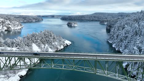 Wide-aerial-view-of-a-black-car-driving-across-Deception-Pass-bridge-during-the-winter
