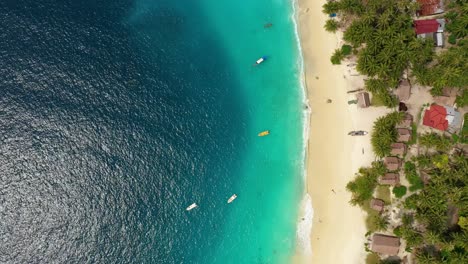 Aerial-view-huts-on-beach-and-turquoise-water-with-boats-on-Asu-Island,-North-Sumatra,-Indonesia