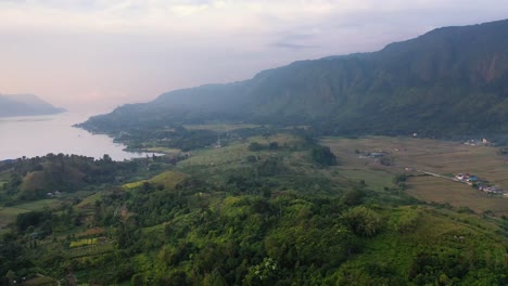 Vista-Aérea-De-Plantaciones-Y-Campos-Debajo-De-Grandes-Colinas-En-La-Isla-Samosir-En-El-Lago-Toba-En-El-Norte-De-Sumatra,-Indonesia
