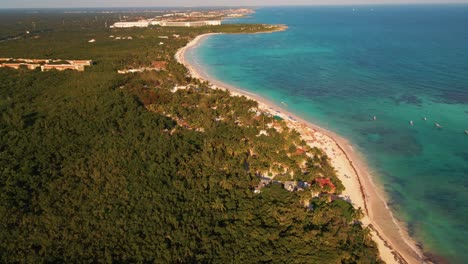 Circling-around-the-point-where-the-dense-Mexican-forest-land-meets-the-Caribbean-sea-waters-on-the-iconic-beachfront-of-Playa-Paraiso-in-Tulum,-Mexico