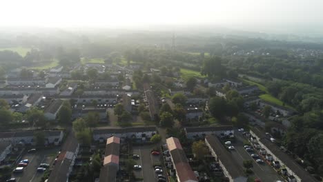 Elevated-aerial-view-over-residential-British-town-houses-during-hazy-golden-hour-pan-right
