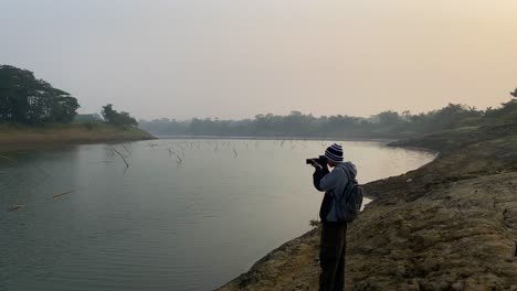 Photographer-shooting-polluted-river-scene-on-misty-day-with-camera,-static