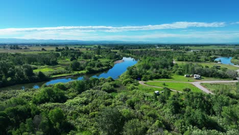 Exuberante-Vegetación-Que-Rodea-El-Río-Tranquilo-En-Saint-Anthony,-Idaho---Toma-Aérea-De-Drones