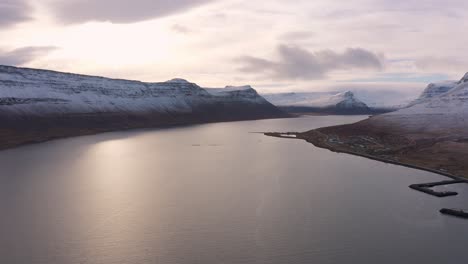 Astonishing-aerial-view-of-Iceland-fjord-landscape-above-sea,-sunset,-lowering