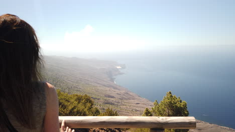 A-woman-with-her-back-turned,-admires-the-spectacular-landscape-that-can-be-seen-from-the-La-Peña-viewpoint-on-the-island-of-El-Hierro-on-a-sunny-day
