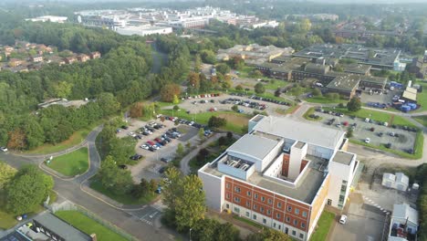 Aerial-view-rising-over-British-hospital-car-park---medical-buildings