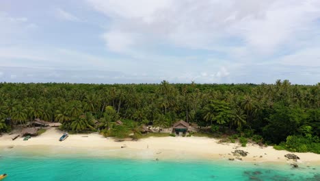 Luftaufnahme-Einer-Frau-Im-Badeanzug,-Die-Am-Tropischen-Strand-Mit-Bungalows-Und-Palmen-In-Indonesien-Spazieren-Geht