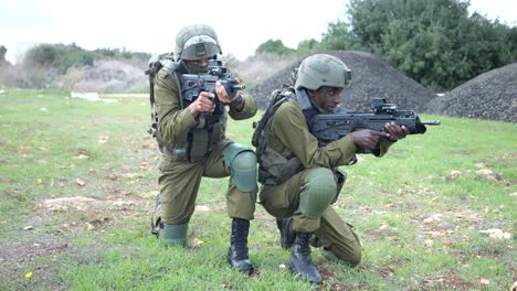 Team-of-IDF-Israel-Army-Infantrymen-Soldiers-Holding-Kneeling-Position-Aiming-Machine-Guns-At-Training-Ground-Outdoors--full-body-shot