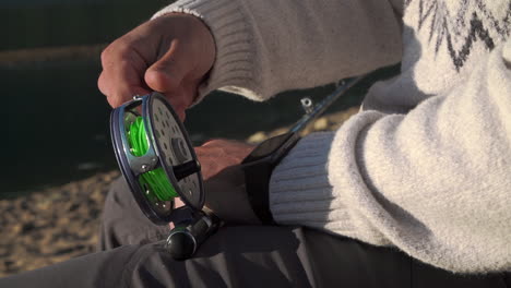 Close-up-of-a-male-fisherman's-hands-prepping-a-fly-fishing-reel
