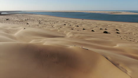 over-flight-of-dunes-and-view-on-the-horizon-of-the-Naila-lagoon-located-in-the-province-of-Tarfaya,-sahara,-morocco