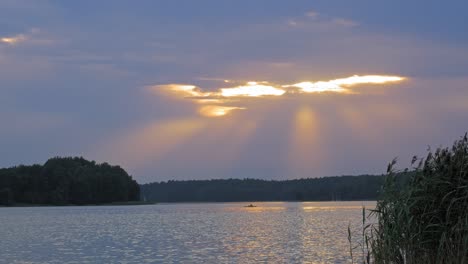 Sunset-rays-beaming-from-the-night-sky-reaveling-kayak-at-the-Wdzydze-Landscape-Park-Poland