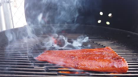 Placing-a-marinated-wild-salmon-steak-on-the-barbecue-and-watching-it-flame-up