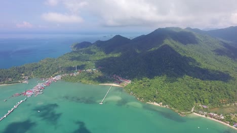 Aerial-side-pan-shot-of-a-fishing-and-tourist-pier-in-Koh-Chang-with-sea,-Jungle-and-mountains
