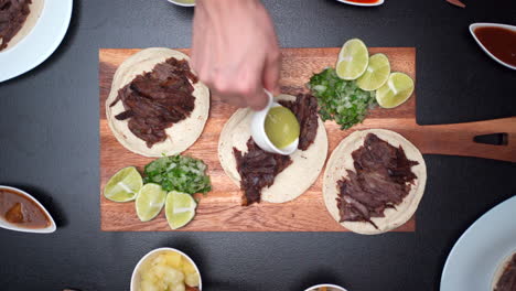Salsa-Zu-Einem-Mexikanischen-Taco-Geben,-Dann-Aufheben-Und-Zur-Mexikanischen-Fiesta-Der-Draufsicht-Der-Linse-Heben