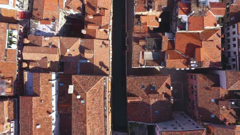 Aerial-view-zooming-into-canal-and-roofs-on-a-sunny-day-in-Venice-in-Italy-in-4k