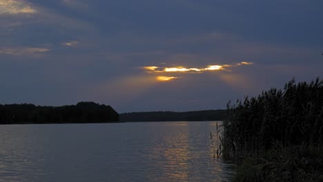 Goldener-Sonnenuntergang,-Der-Sich-Durch-Die-Wolken-über-Dem-Ruhigen-See-Im-Wdzydze-landschaftspark-In-Polen-Versteckt---Breite-Aufnahme