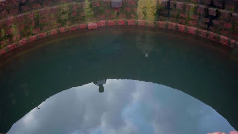 refection-of-sky-and-person-looking-in-well