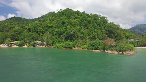 Aerial-side-dolly-of-a-small-beach-and-rocky-coastline-on-Koh-Chang-with-small-guest-houses-and-Jungle-and-ocean