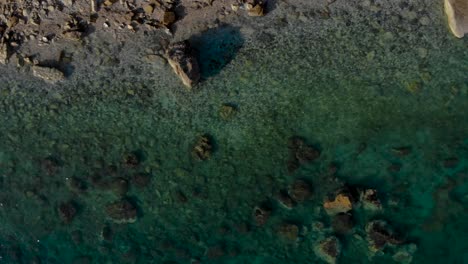 Cliffs-and-pebbles-under-turquoise-sea-water-on-a-remote-beach-in-Mediterranean-seaside