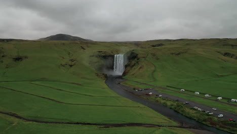 Drone-Flying-Towards-Skogafoss,-A-Beautiful-Waterfall-In-The-Skoga-River,-Surrounded-By-Lush-Landscape-In-South-Iceland---aerial