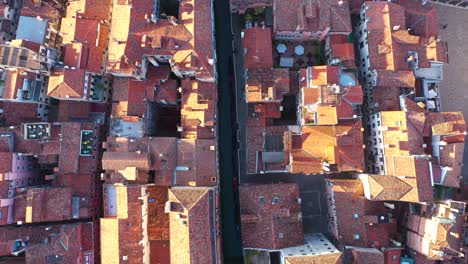 Aerial-view-zooming-out-of-canal-and-roofs-on-a-sunny-day-in-Venice-in-Italy-in-4k