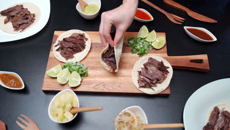 Picking-up-mexican-beef-tacos-of-cutting-table-top-view