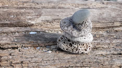 Small-textured-beach-rocks-balanced-zen-like-on-wooden-beach-sleeper