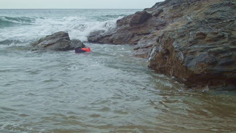 Life-jacket-floats-along-beach-rocks-as-waves-crash-on-shore