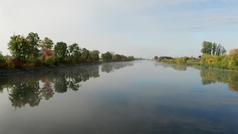 Low-altitude-flight-over-smooth-flat-surface-of-river-in-early-morning-light