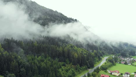 Aerial-of-Misty-Mountain-Village-in-the-Alps-next-to-massive-Forest