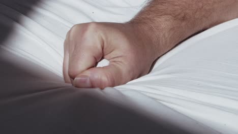 Close-up-of-male-hand-grasping-the-bedsheet-while-reaching-climax-during-sex