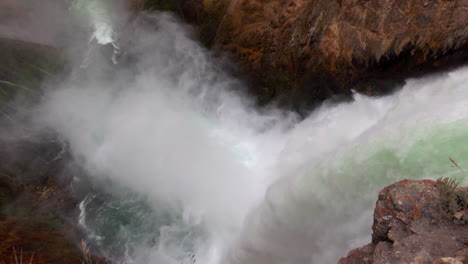High-angle-shot-of-Yellowstone's-Upper-Falls-with-mist-blowing-out-from-base-of-falls