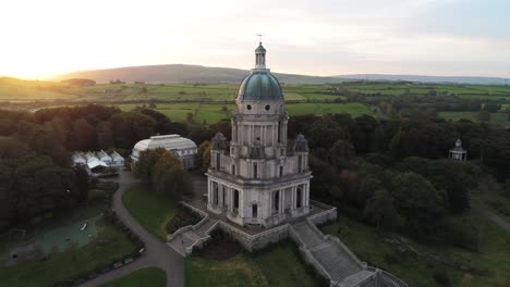 Sunrise-passing-wealthy-Ashton-memorial-historical-building-dome-Lancaster-countryside-aerial-orbit-right-view