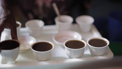 Coffee-is-Served-by-African-Woman,-Many-Small-Cups,-Close-Up-Hands