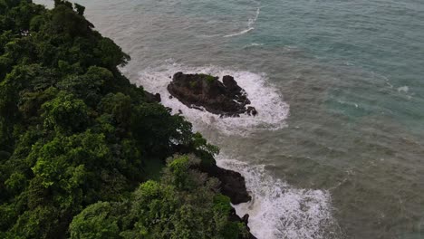 Island-aerial-view-splashing-waves-ocean-tide-against-rocky-coastline-Thailand