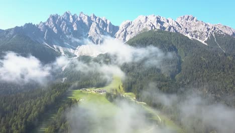 Aerial-over-the-clouds,-A-Ski-slope-during-summer-taken-from-Sporthotel-Tyrol-in-Innichen,-Dolomite-Italy