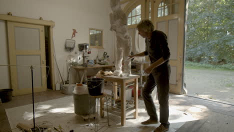 Sculptor-placing-plaster-on-sculpture-in-workshop---wide