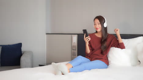 Attractive-young-lady-listening-to-relaxing-music-on-her-wireless-headphones-from-a-mobile-app-or-radio
