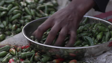 African-Marketplace,-Woman-Grabs-Jalapeno-Shishito-Peppers-From-Bowl,-Close-Up-Hand